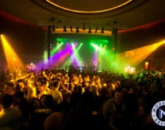 Live-Konzert mit bunter Bühnenbeleuchtung und tanzender Menschenmenge in einer Veranstaltungshalle