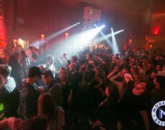 Tanzende Menschenmenge in einem Club mit bunten Scheinwerfern und DJ-Pult im Hintergrund bei Moderns Bremen