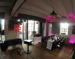 Hochzeits-DJ-Setup in festlich beleuchteter Eventlocation mit pinker Akzentbeleuchtung und gedeckter Tafel