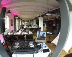 DJ-Pult mit Pioneer-Controller und Laptop in Restaurant mit festlich gedeckten Tischen und bunter Beleuchtung