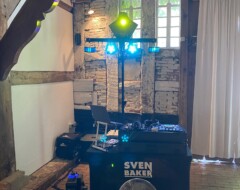 DJ-Setup von Sven Baker mit beleuchteter Anlage in rustikalem Raum mit Holzbalken und Steinwand für Hochzeit