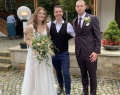 Brautpaar mit Hochzeits-DJ nach der Trauung vor einer Eventlocation im Freien