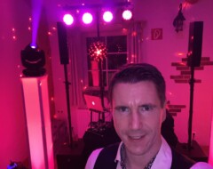 Hochzeits-DJ Sven Baker im Selfie vor professioneller Lichtanlage und DJ-Equipment in pink-violettem Licht