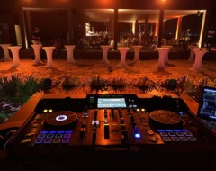 Pioneer DJ-Controller vor Tanzfläche mit beleuchteten Stehtischen und Gästen bei einer Abendveranstaltung