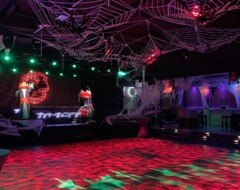 Halloween-Party mit leuchtender Tanzfläche in Rot und Grün, Spinnweben-Deko an der Decke und Grusel-Figuren im Raum